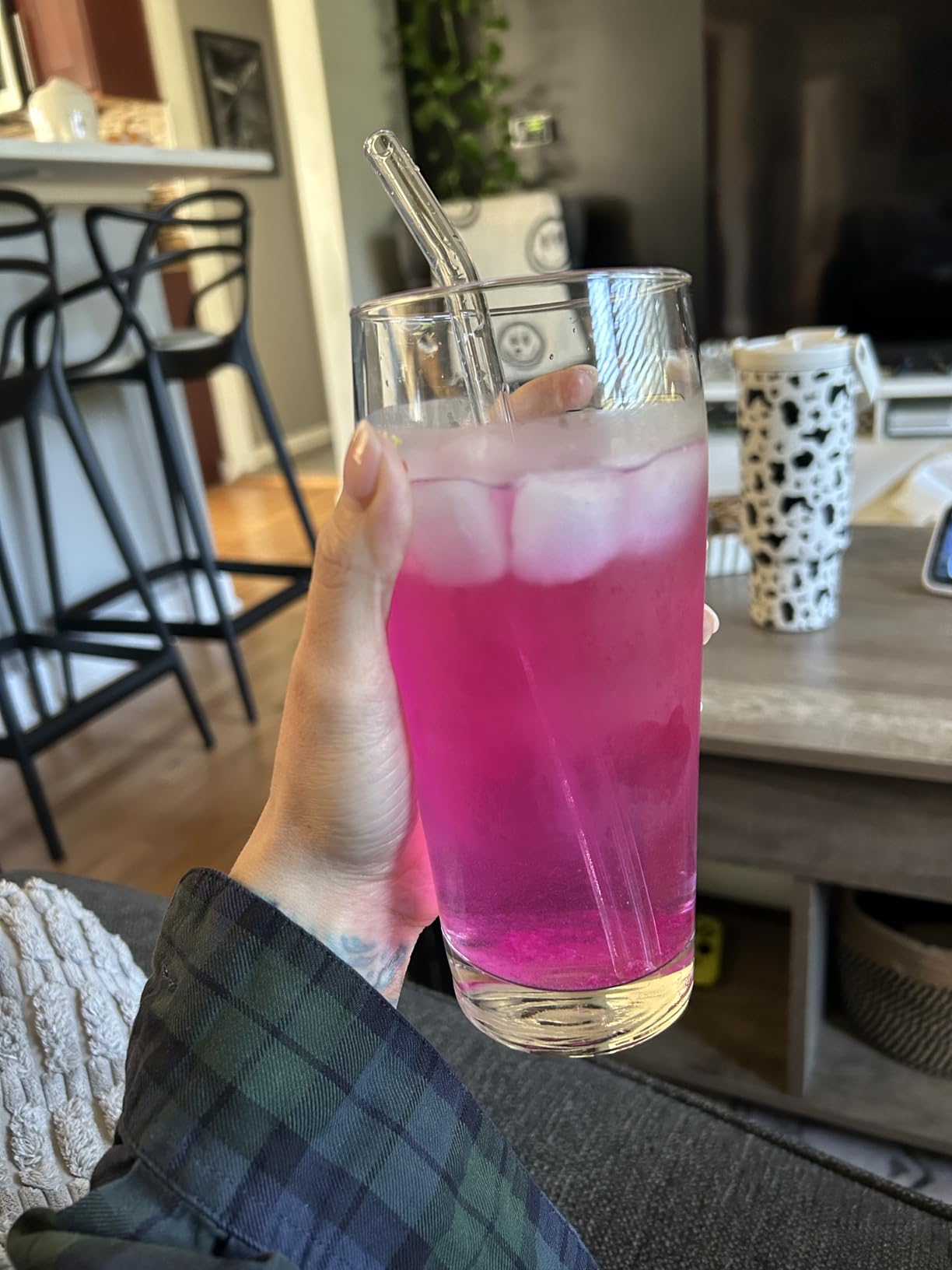 Customer relaxing on the sofa with a tall glass of bright pink Tavo LiquidCalm liquid calm drink with ice.